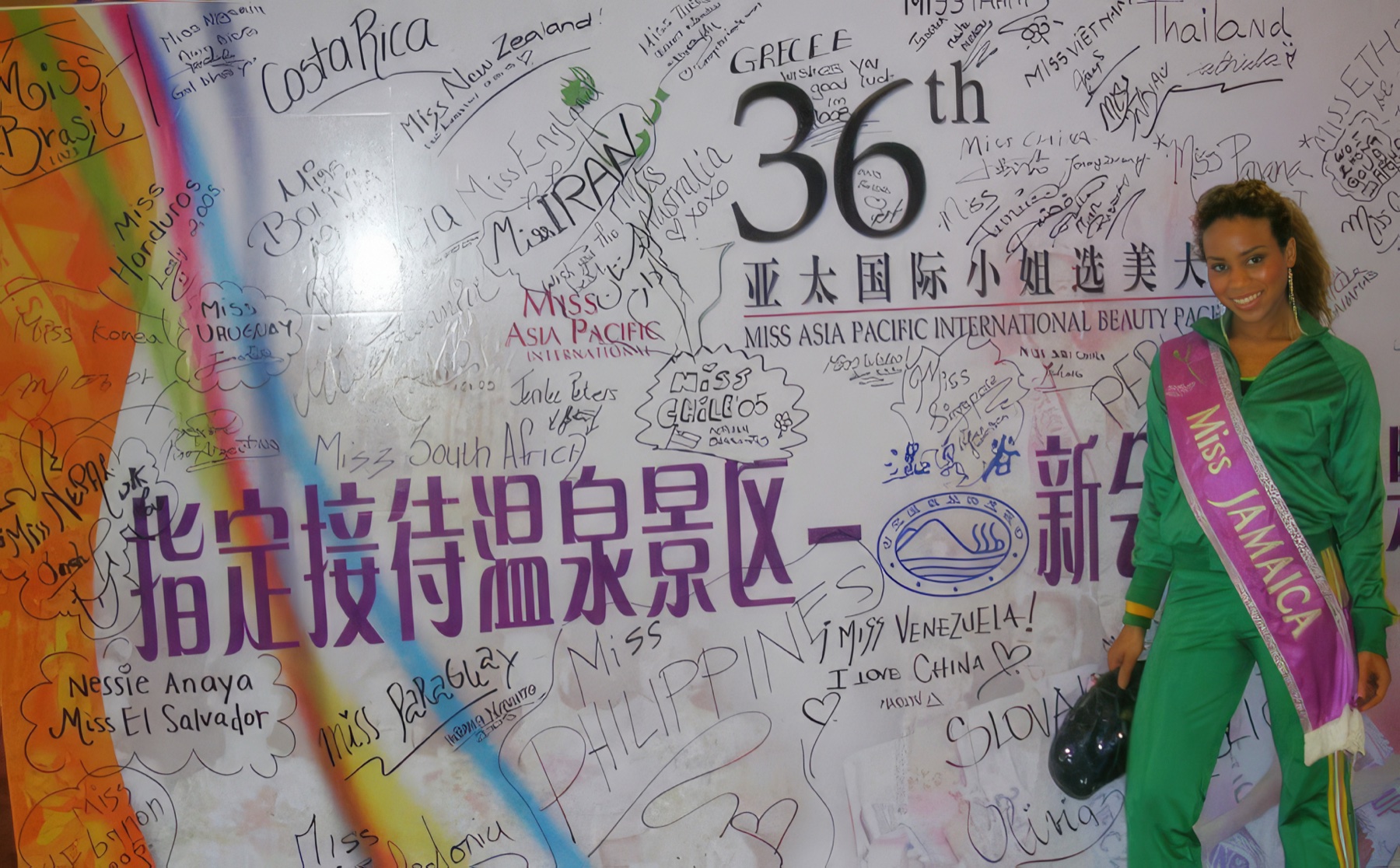Daisi beside the Miss Asia Pacific International backdrop covered with delegates’ signatures.