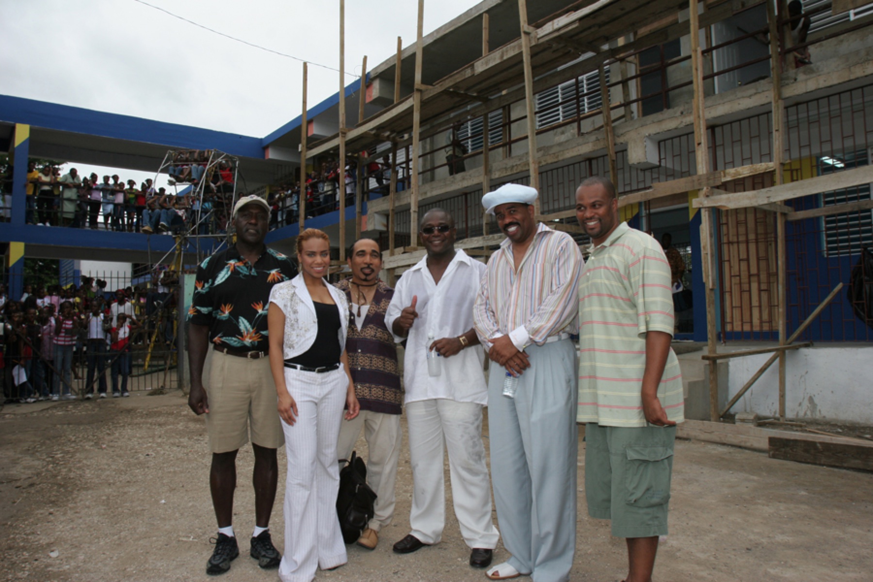 Daisi and a group of participants outside a school building, with students gathered in the background.