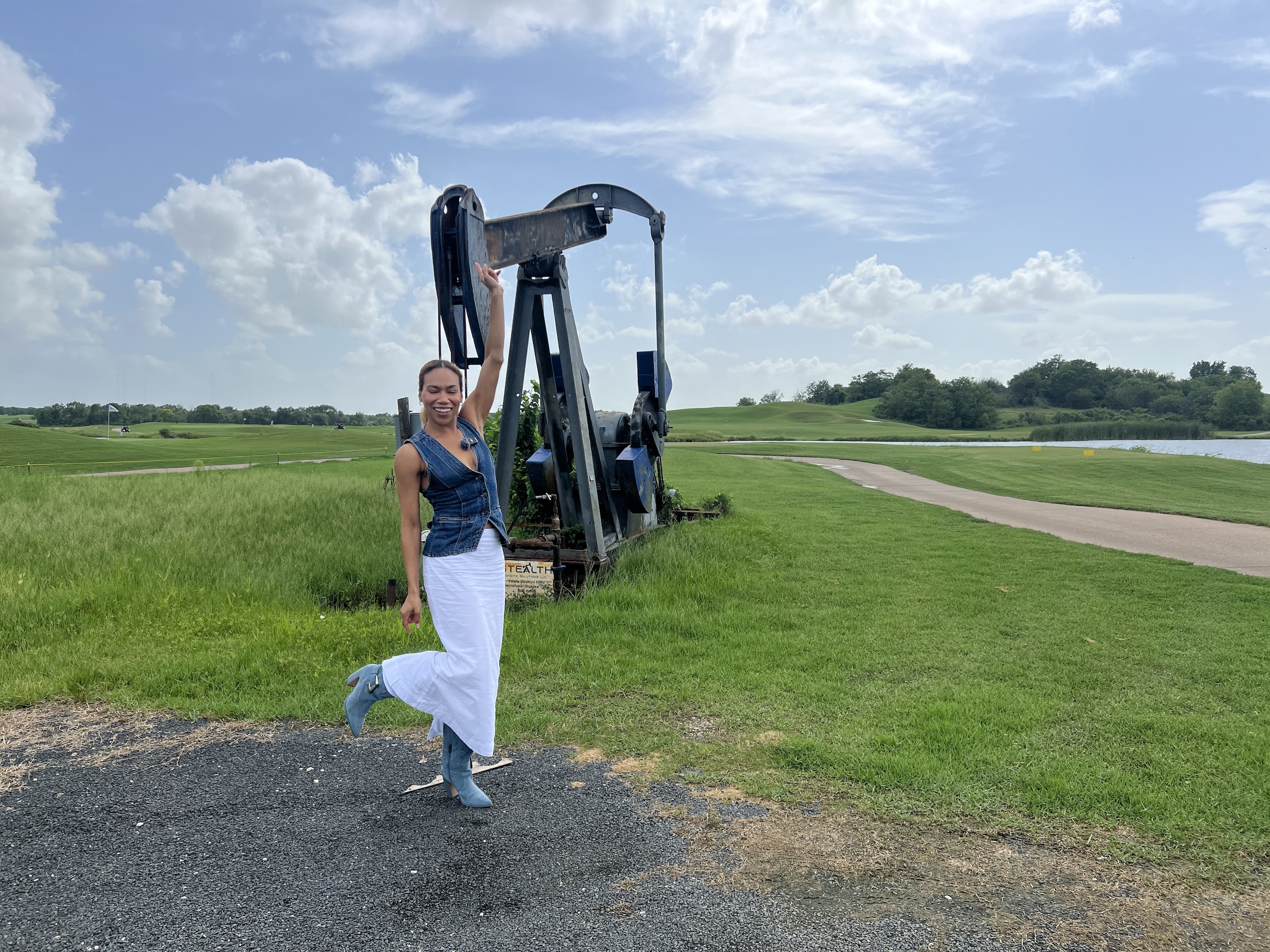 Daisi standing beside an oil pumpjack in a green Texas landscape